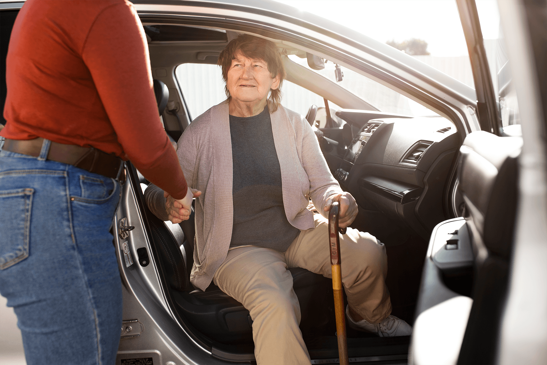 A smiling young man in the driver's seat of an ambulatory transport conversing with an older man in the backseat