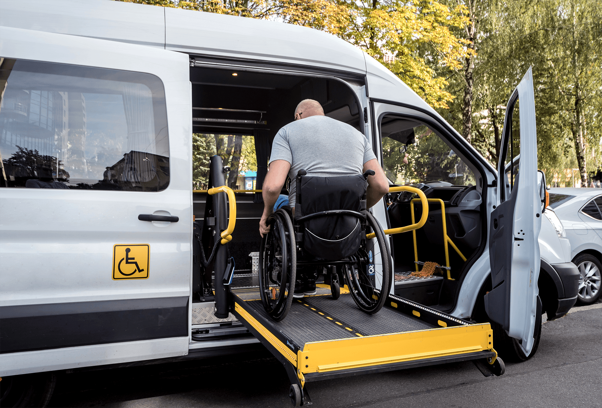 Passenger in a wheelchair boarding a transport van via the rear ramp